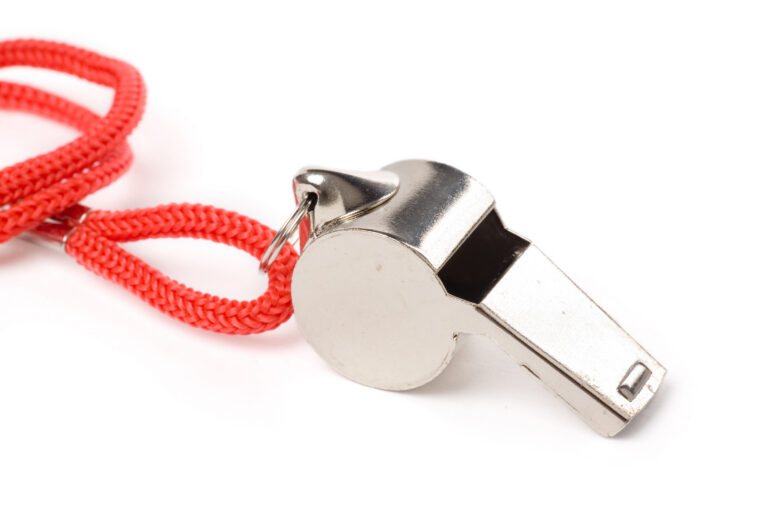 Close-up of a metal whistle attached to a red lanyard on a white background, symbolizing whistleblowing and reporting misconduct.