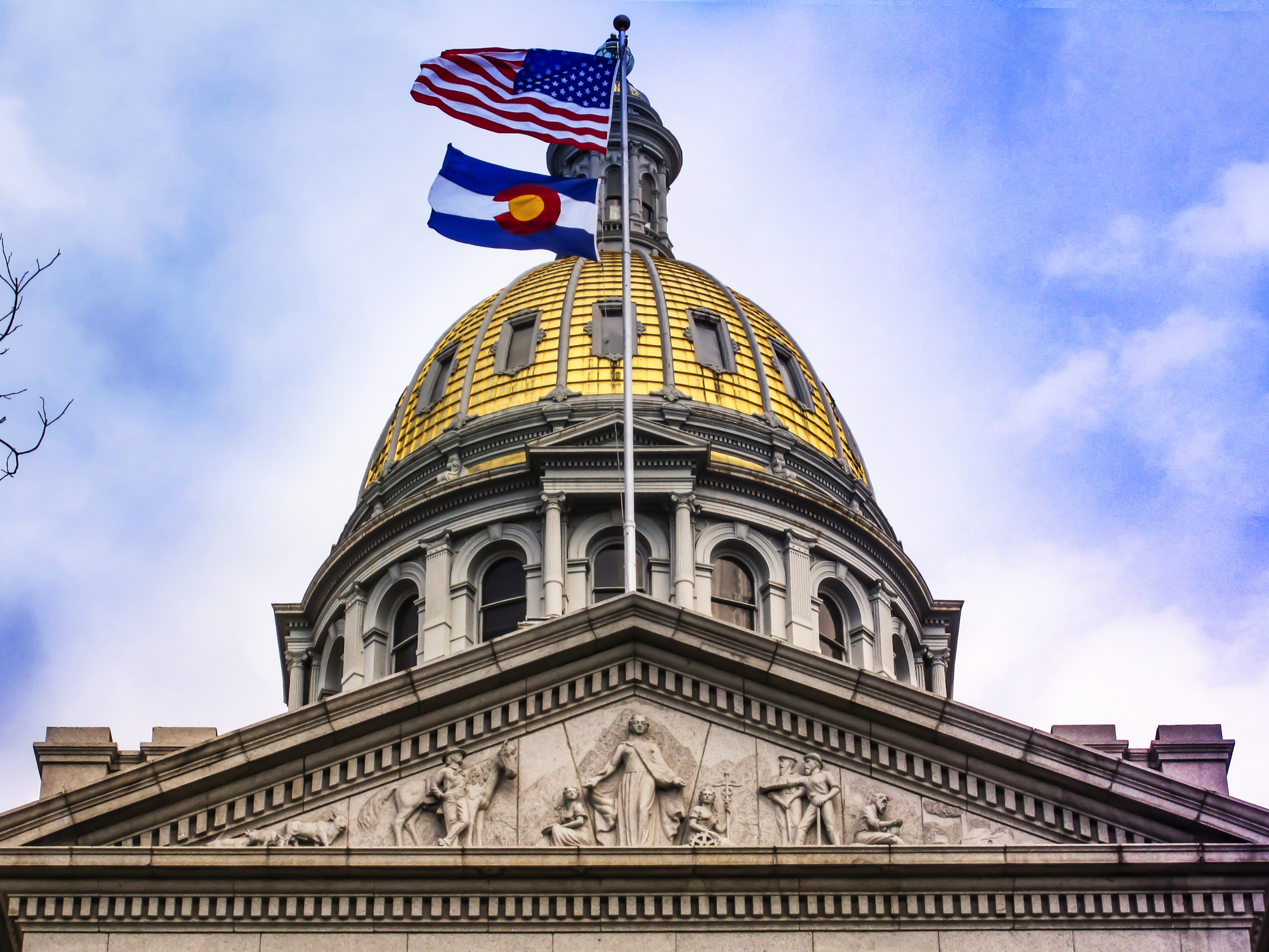 Colorado State Capitol dome with the American and Colorado flags flying above the building in Denver.